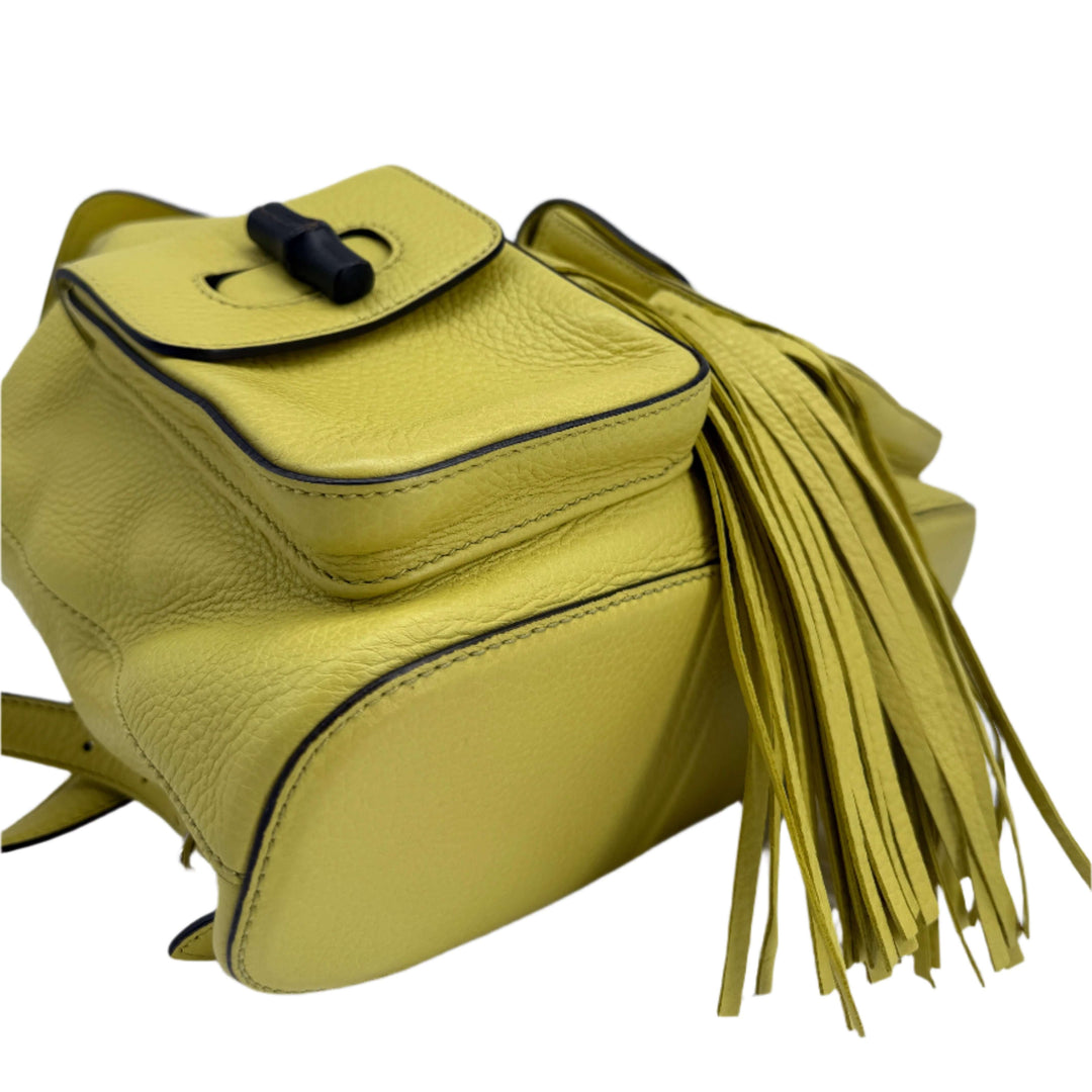 Gucci Medium Bamboo Backpack in vibrant mimosa yellow calfskin with structured design and tassel detailing.