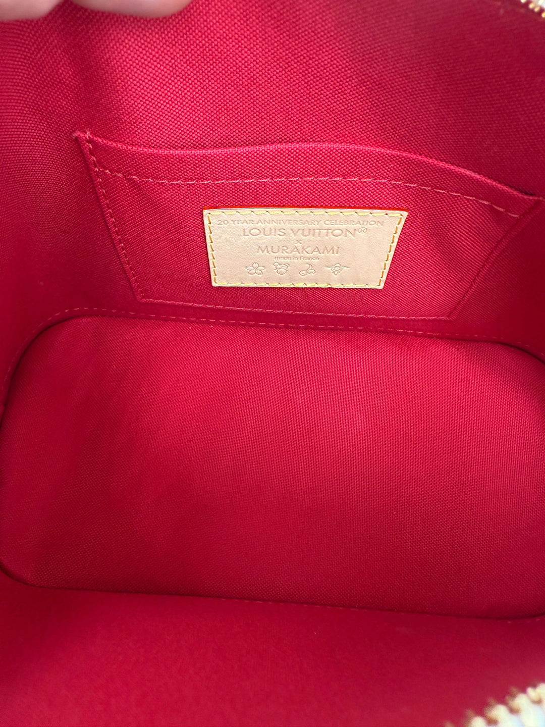 Interior view of Louis Vuitton x Takashi Murakami Alma BB bag featuring vibrant red lining and designer label.