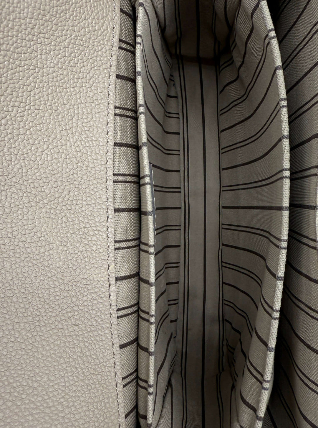 Interior view of Louis Vuitton Pochette Métis with beige leather and striped fabric lining.