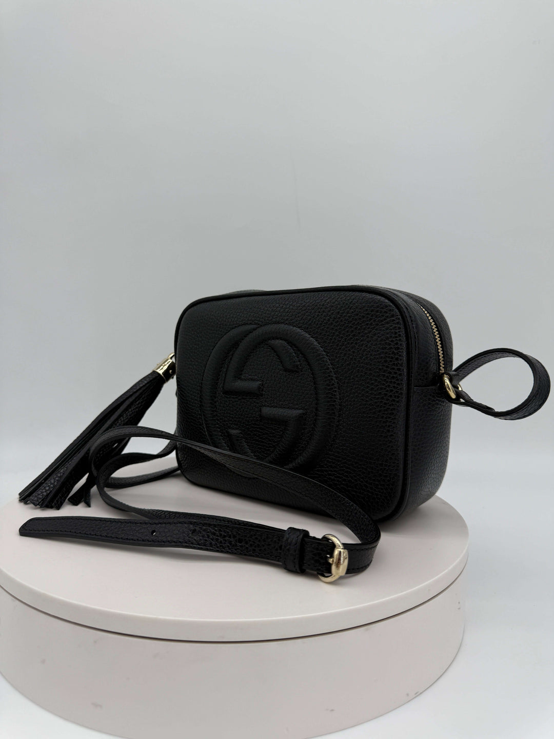 Gucci Small Soho Disco Bag in black pebbled calfskin leather with gold tassel and interlocking G logo.
