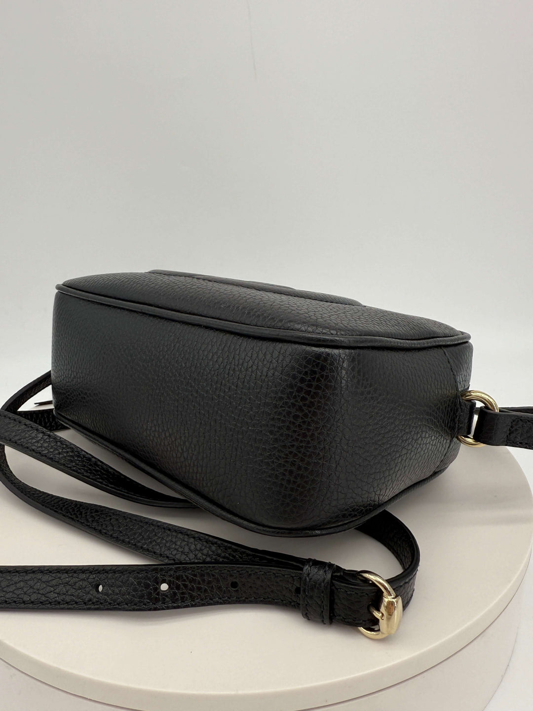 Gucci Small Soho Disco Bag in black pebbled calfskin leather showcasing the side view and gold hardware details.