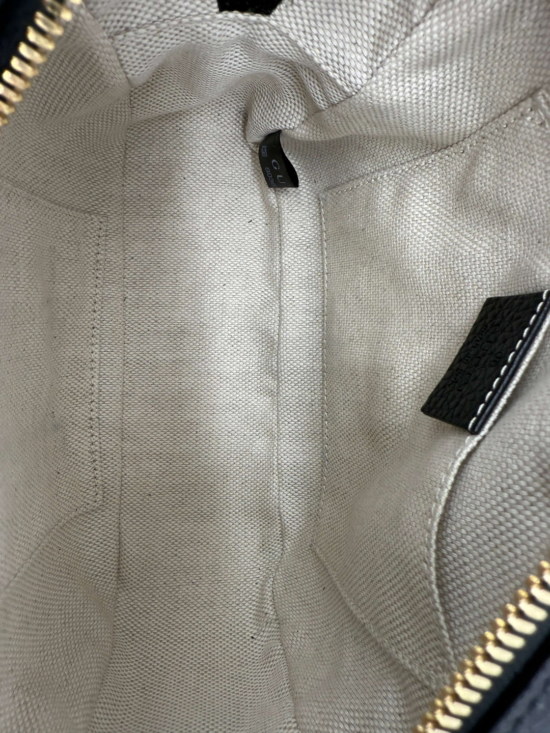 Interior view of Gucci Small Soho Disco Bag showcasing its beige fabric lining and zipper pocket details.