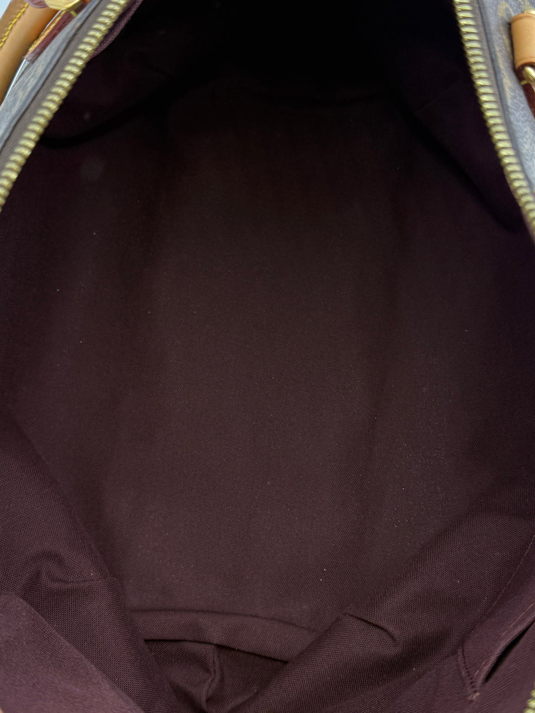 Interior view of the Louis Vuitton Monogram Turenne MM's spacious burgundy lining.