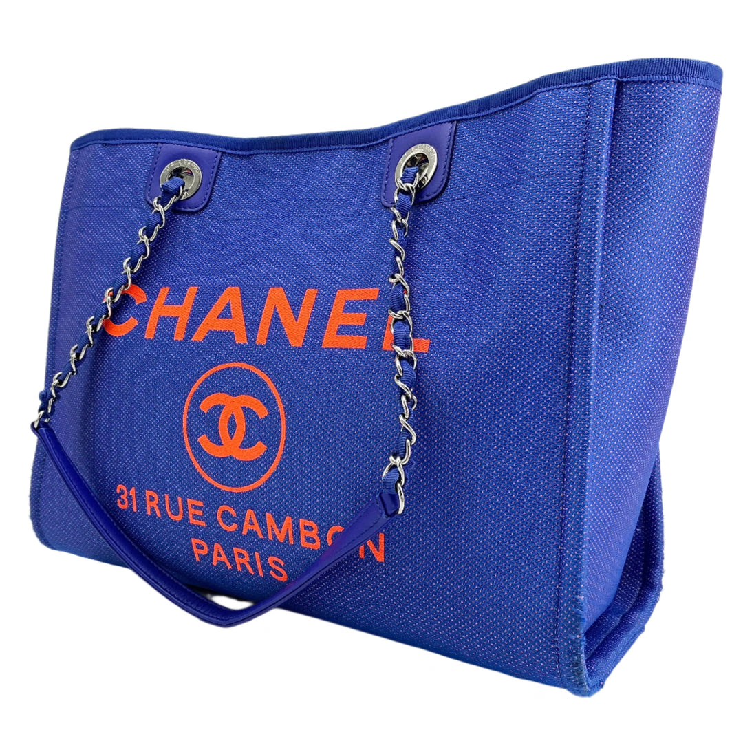 Chanel Small Deauville Tote in blue canvas with orange logo and chain handles, showcasing timeless luxury and vibrant design.