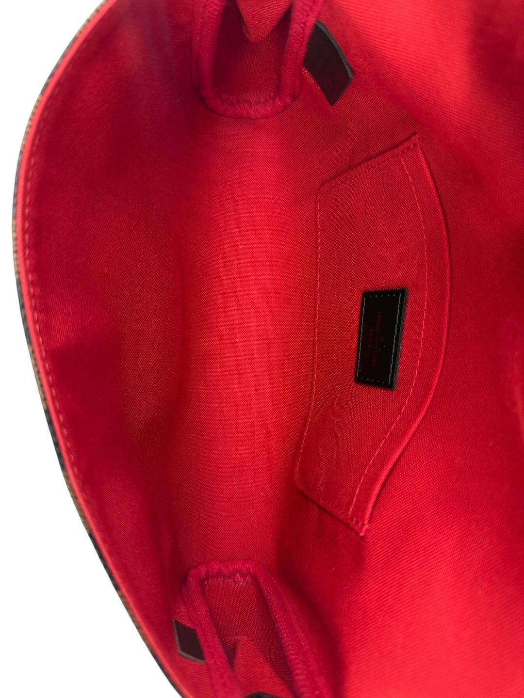Interior view of the Louis Vuitton Damier Ebene Favorite MM Bag | LuxLoveLouis showcasing vibrant red lining and pocket.