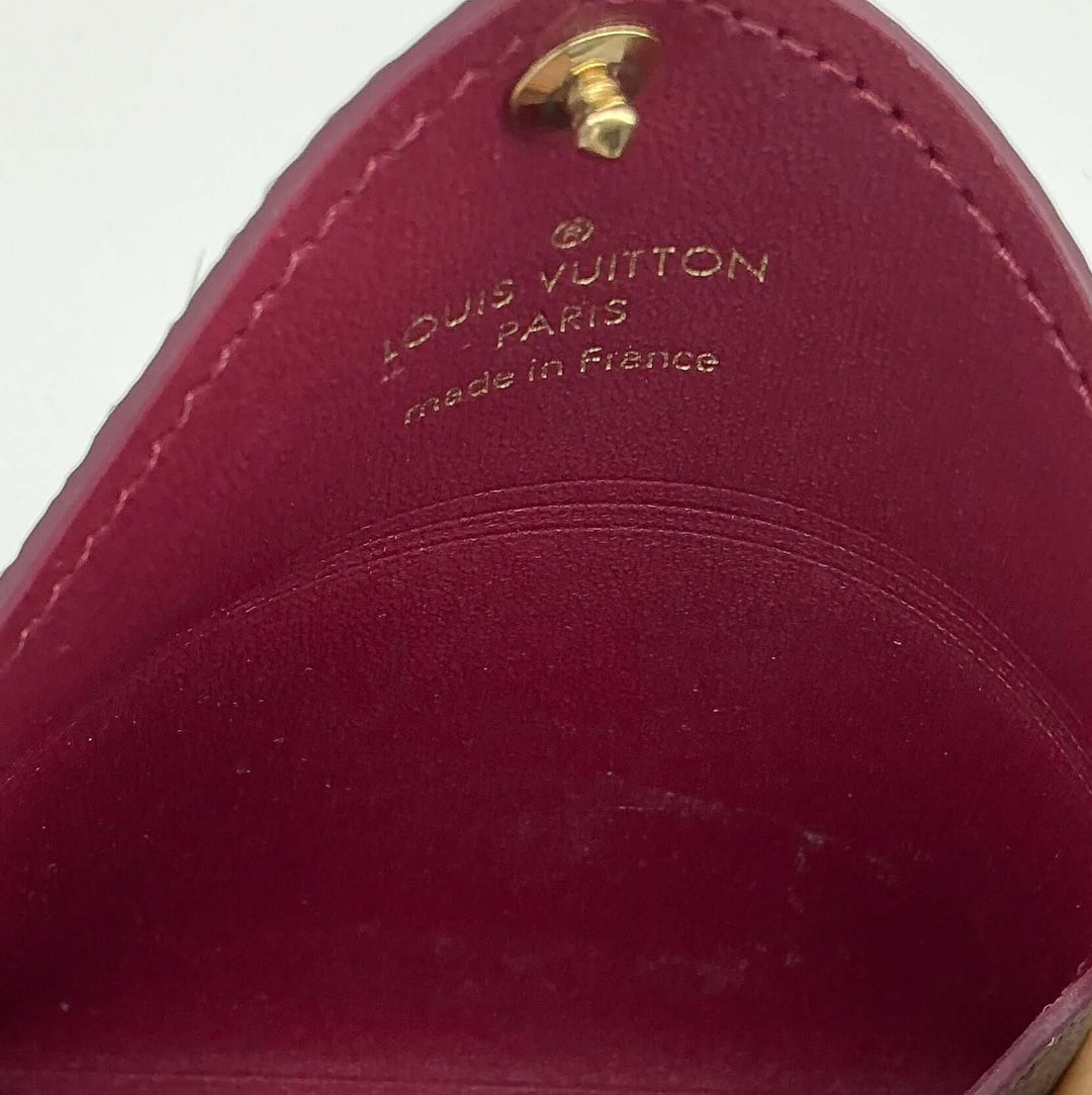 Interior view of Louis Vuitton Small Kirigami Pochette showing fuchsia leather lining and gold-tone snap detail.