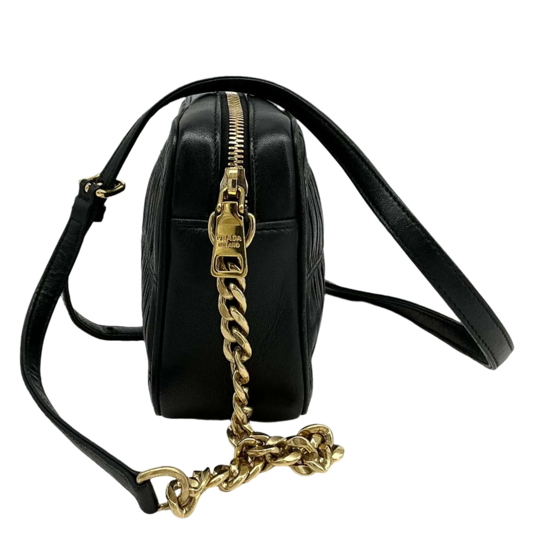 Prada Nappa Gaufre Camera Bag side view showcasing pleated black lambskin leather and gold-tone chain strap.