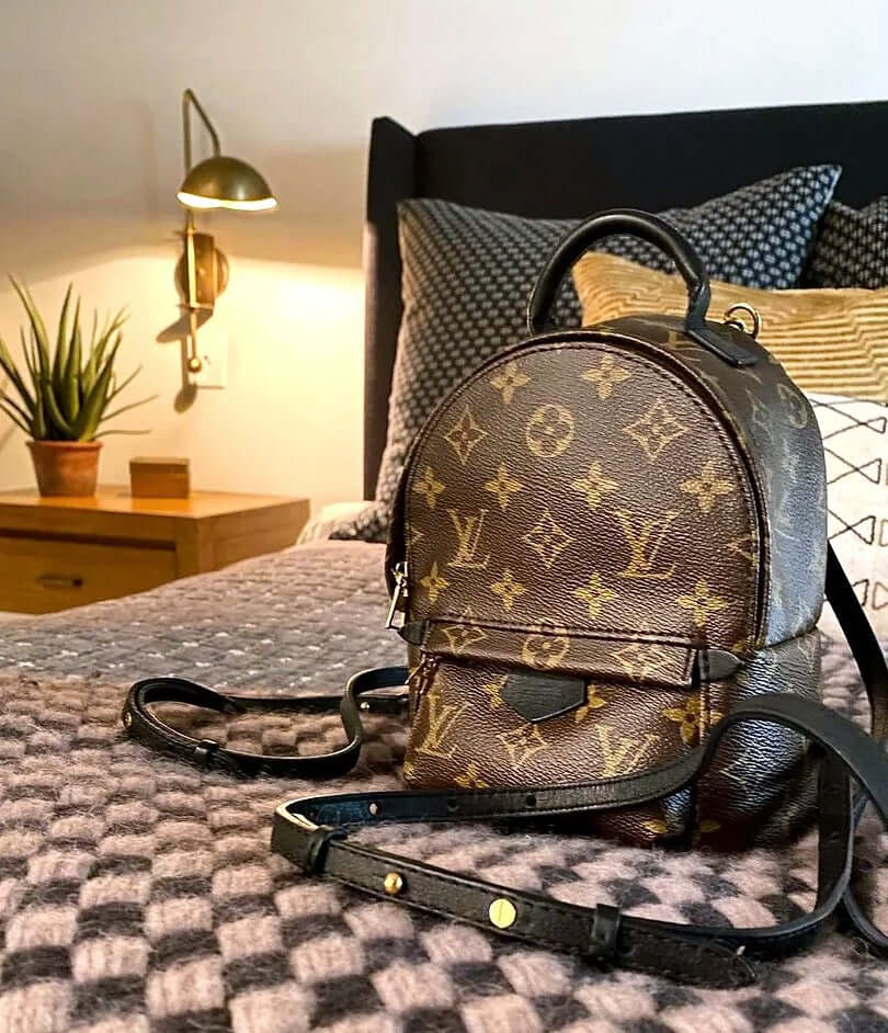 Elegant Louis Vuitton backpack resting on a cozy bedding, showcasing luxury travel accessories in stylish home decor setting.