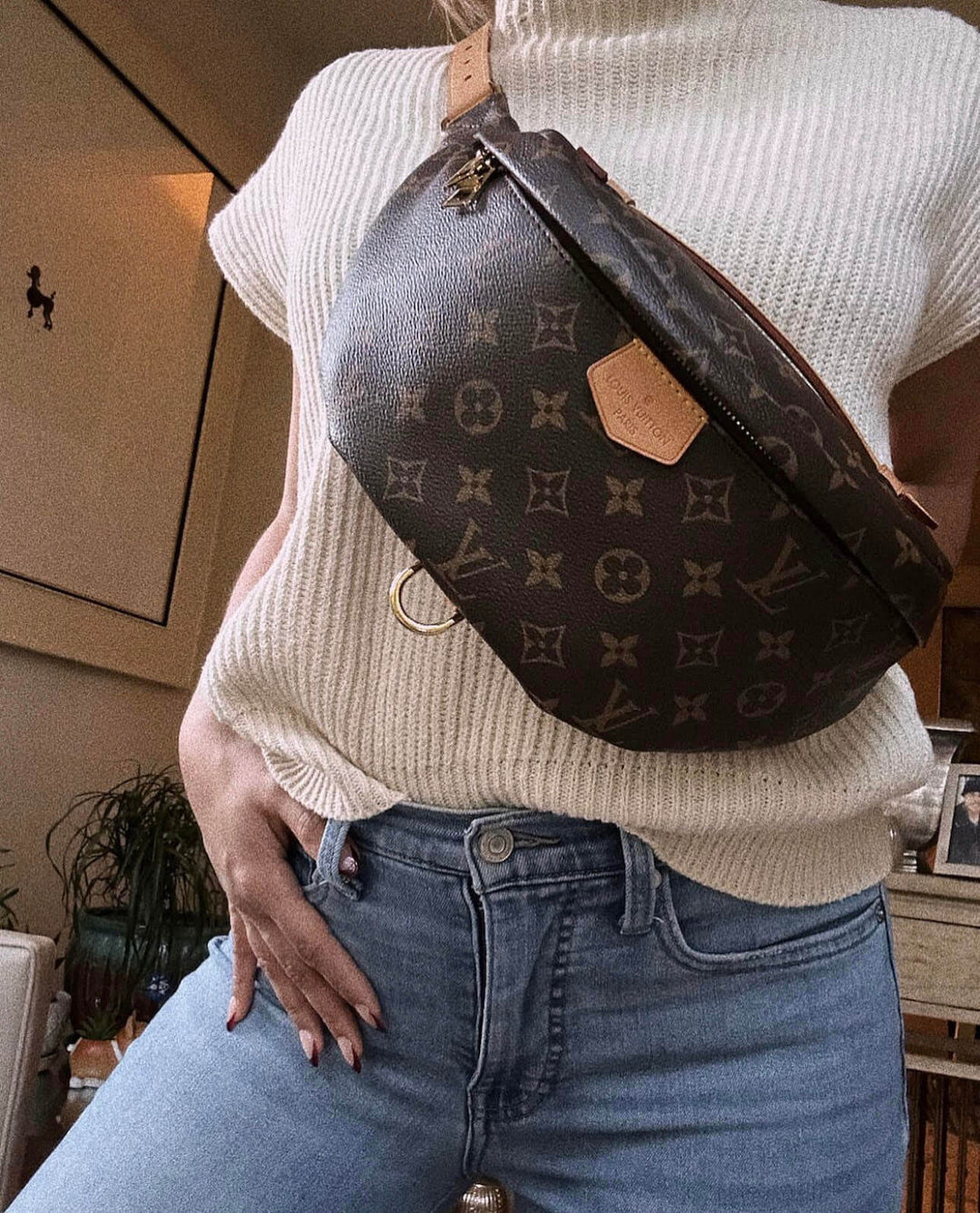 Stylish woman wearing a Louis Vuitton crossbody bag with a cozy sweater and jeans, showcasing modern fashion.