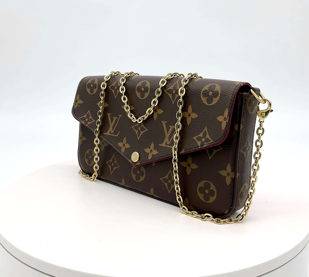 LOUIS VUITTON Monogram Felicie Pochette featuring gold chain strap on a white surface, showcasing the iconic monogram pattern.