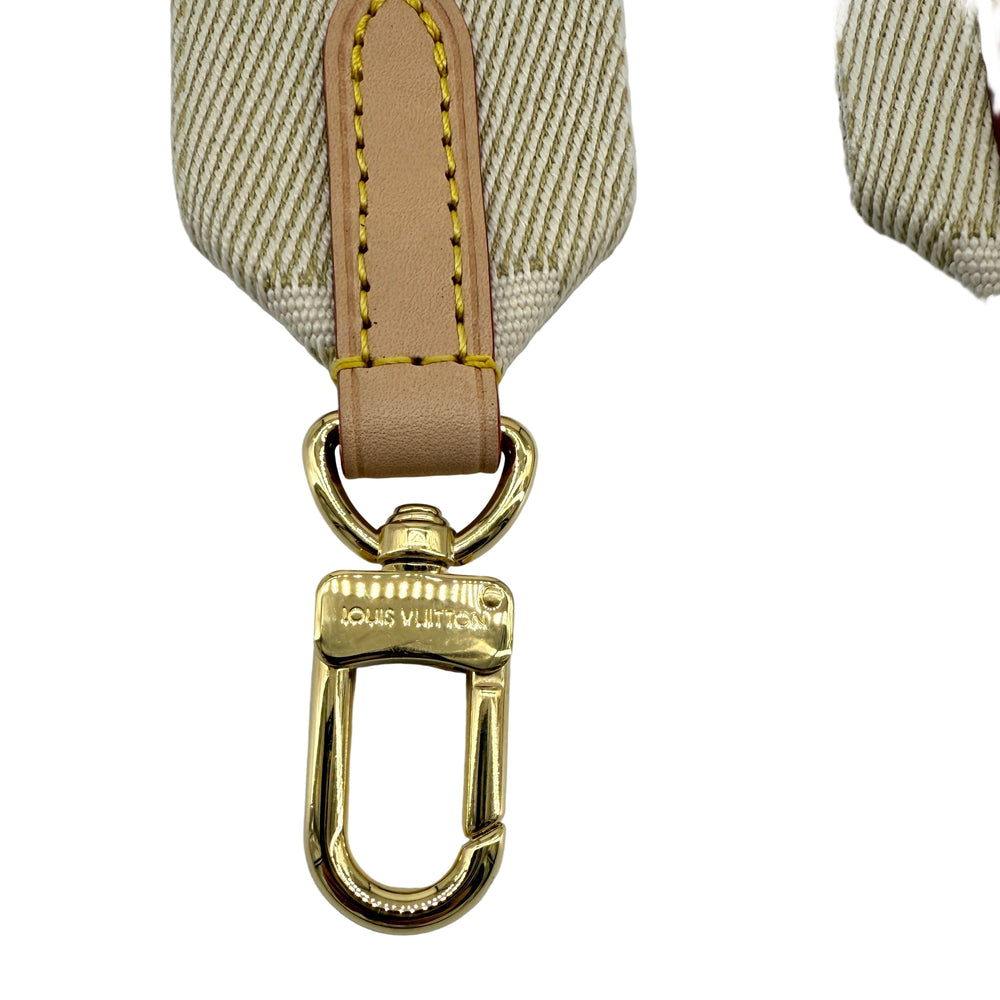 Close-up of Louis Vuitton Bandoulière bag strap clasp in gold hardware with beige fabric.