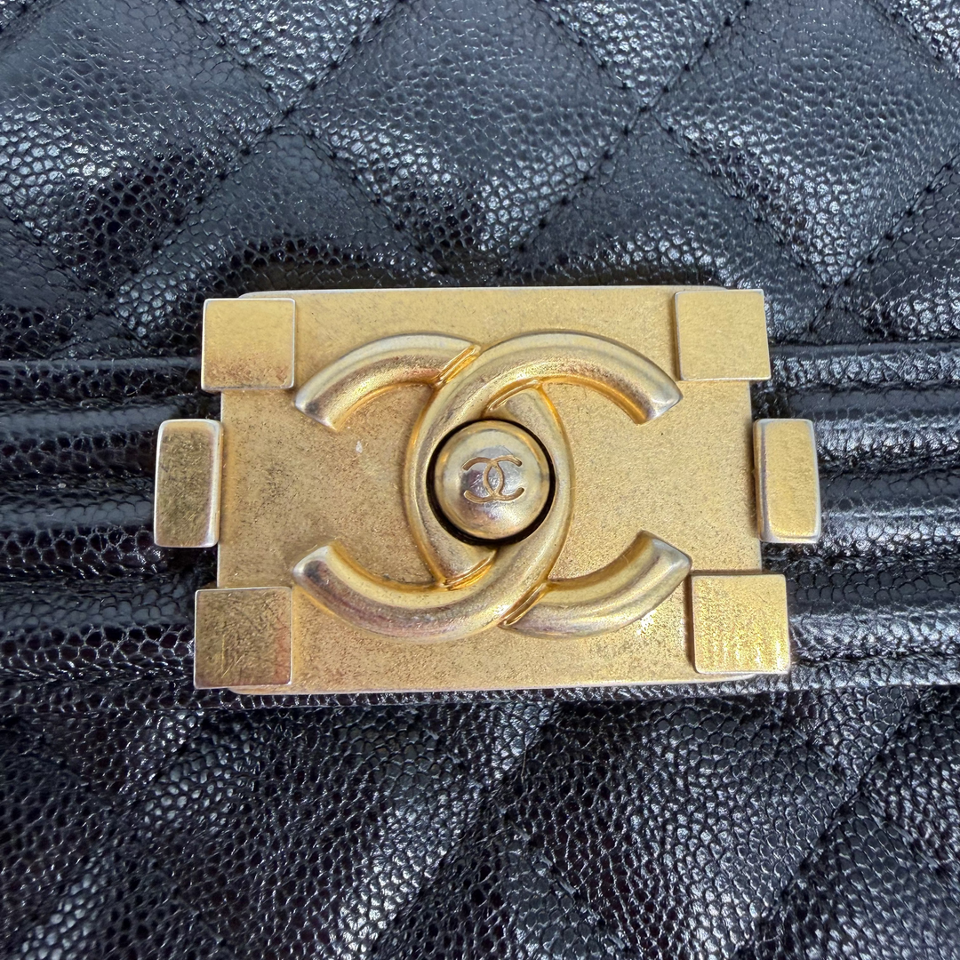 Close-up of Chanel North South Boy aged gold-tone CC push-lock showing visible scratches and finish wear