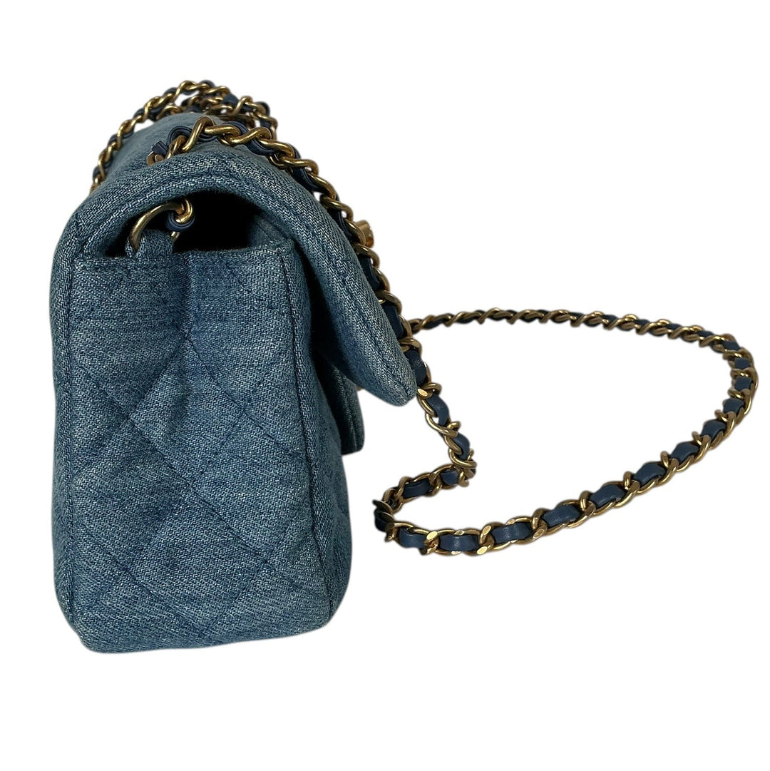 A blue quilted leather shoulder bag with a gold-tone chain strap, shown from a side profile view against a plain white background.