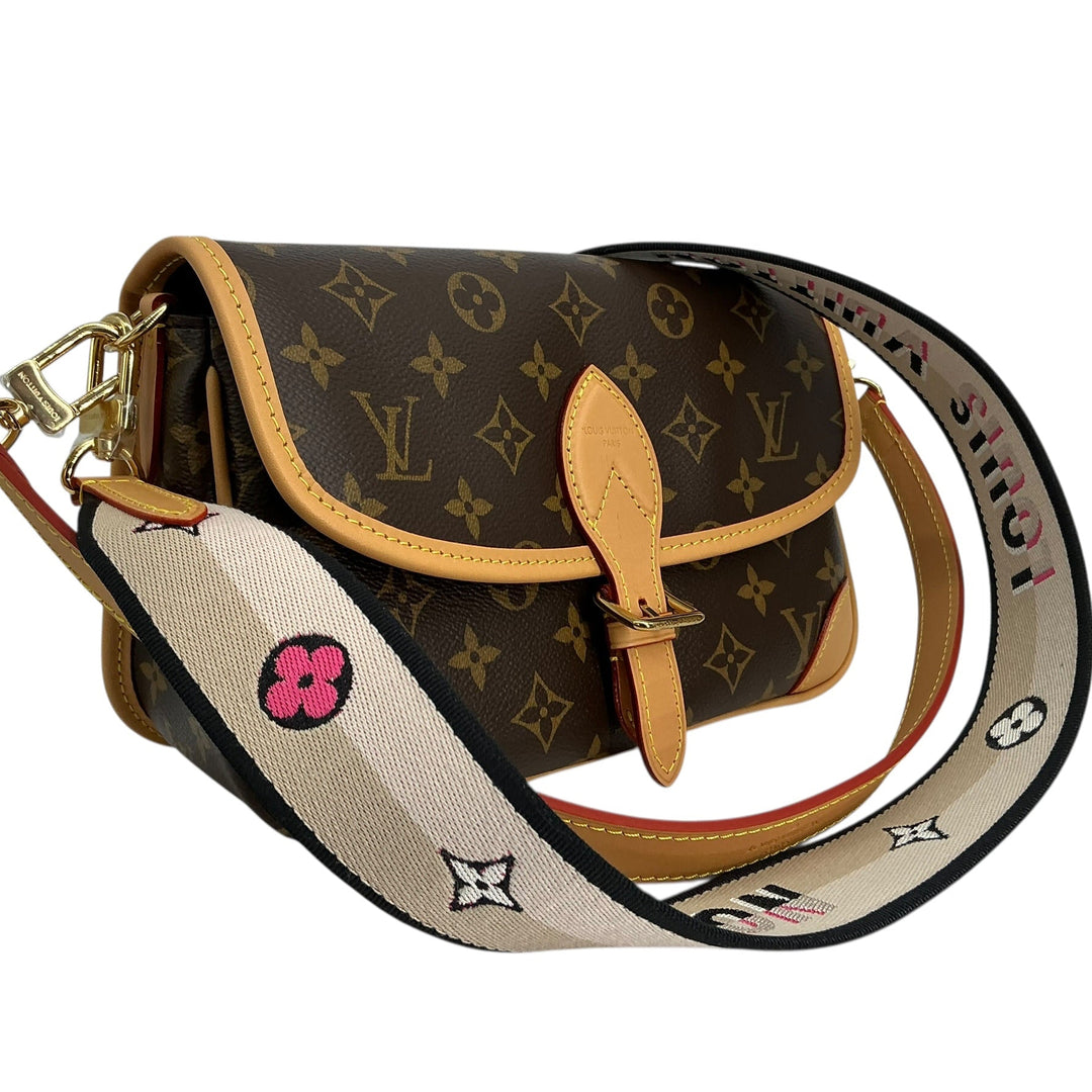 Louis Vuitton Satchel monogram canvas shoulder bag with tan leather trim and a wide beige patterned shoulder strap featuring Louis Vuitton monogram and flower motifs.