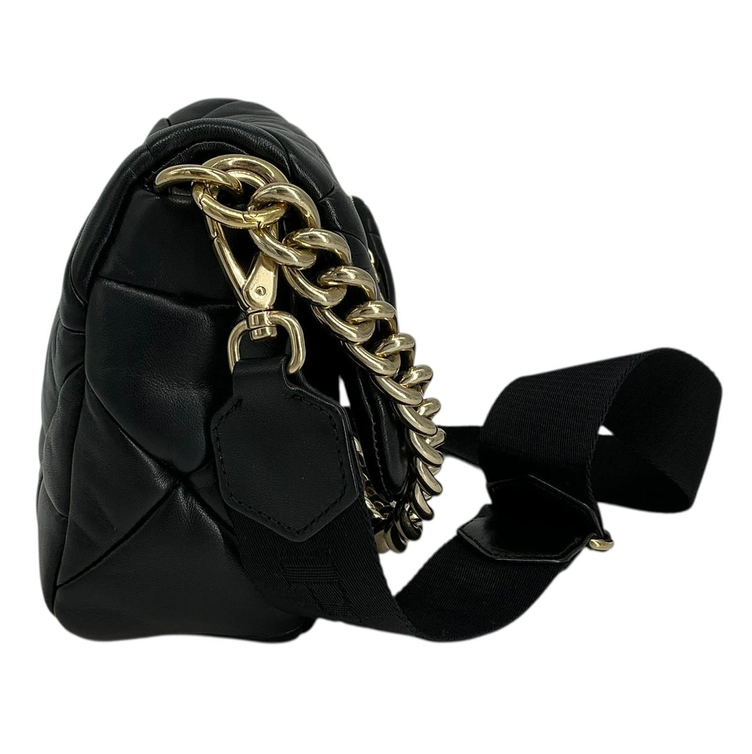 A black quilted leather shoulder bag with a chunky gold chain detail and a black fabric strap, shown from a side profile on a white background.