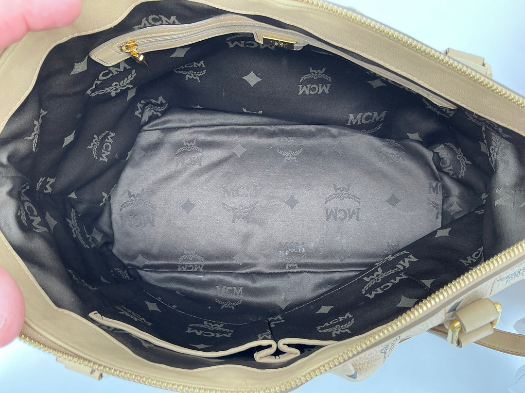 Inside view of MCM Visetos Medium Essentials Shopper Tote in beige, showcasing black monogram lining and spacious interior.