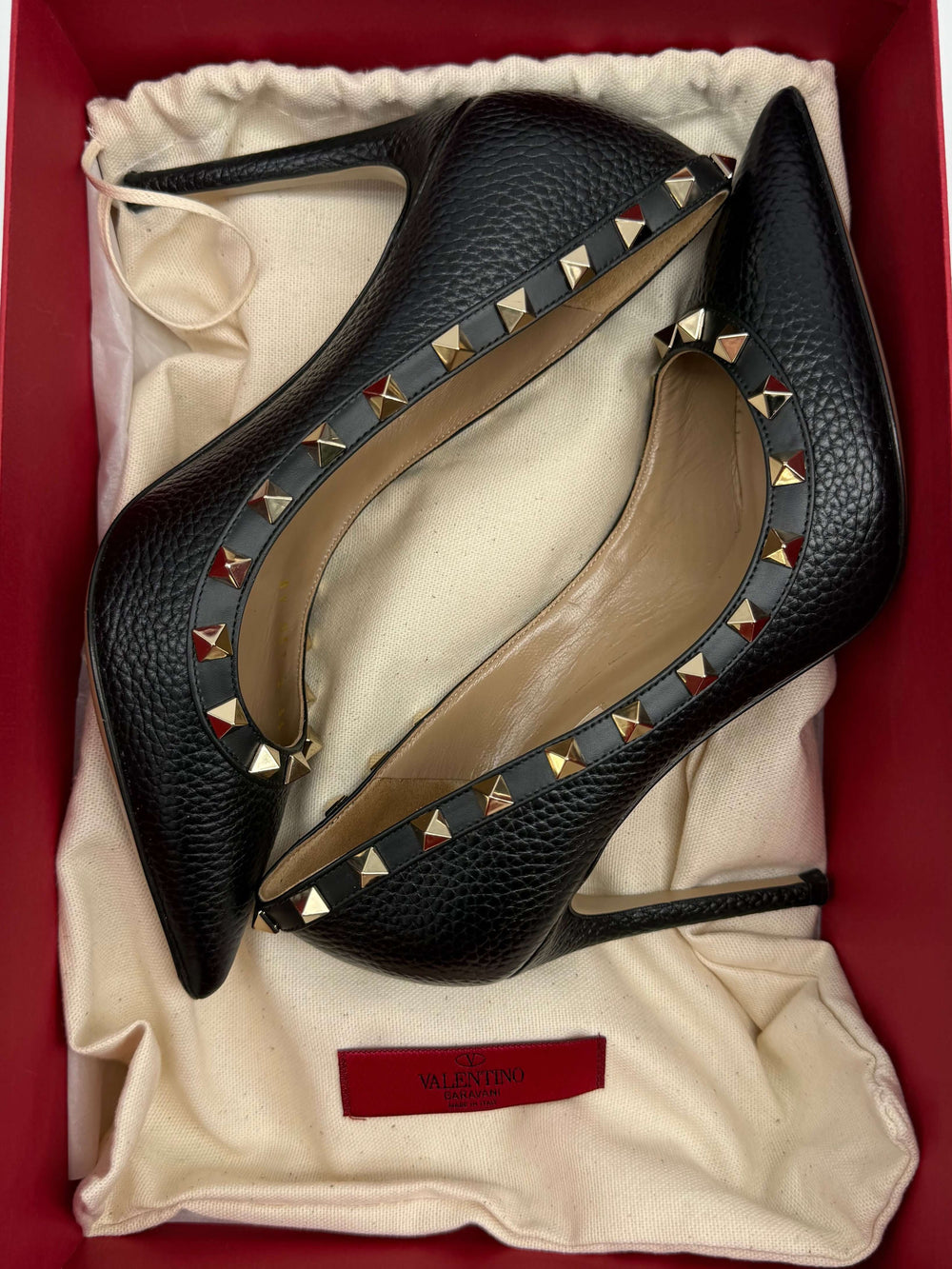 Valentino Garavani black Rockstud pumps in a red box, featuring gold and silver stud detailing on pebbled leather.