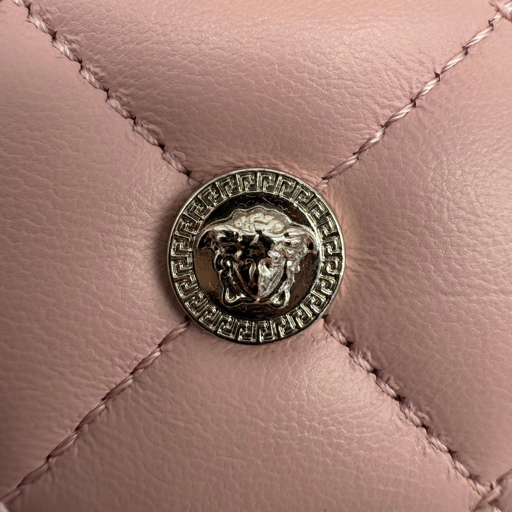 Close-up of Versace Medusa emblem on blush pink quilted leather card holder