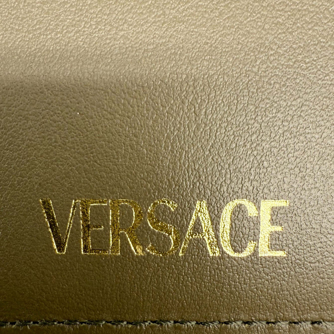 Close-up of the gold embossed 'VERSACE' logo on premium leather.