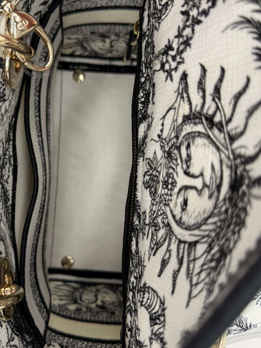 Interior view of Christian Dior Lady D-Lite bag featuring intricate black and white embroidered design and gold hardware.