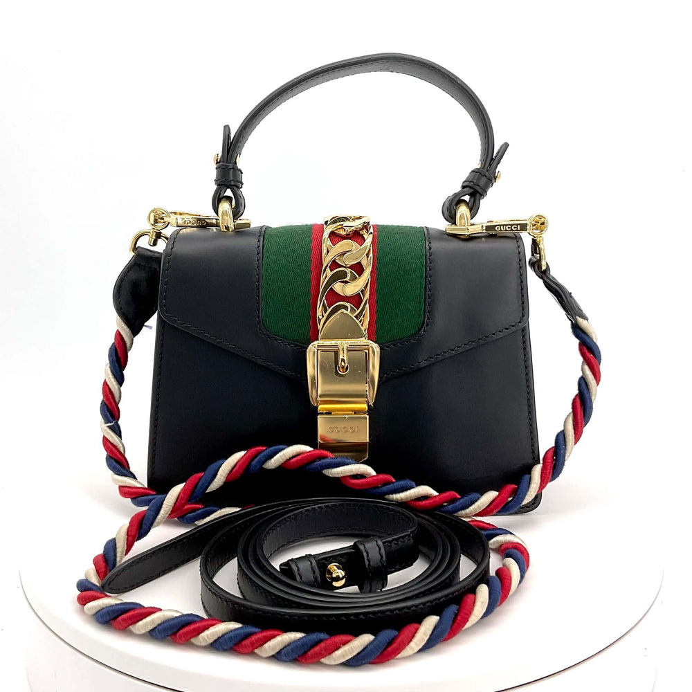 GUCCI Calfskin Mini Sylvie Top Handle Bag in Black|LuxLoveLouis | Elevate your style with the GUCCI Calfskin Mini Sylvie Top Handle Bag in Black. This elegant shoulder bag blends smooth calfskin with classic Gucci web detailing, offering a luxurious acces