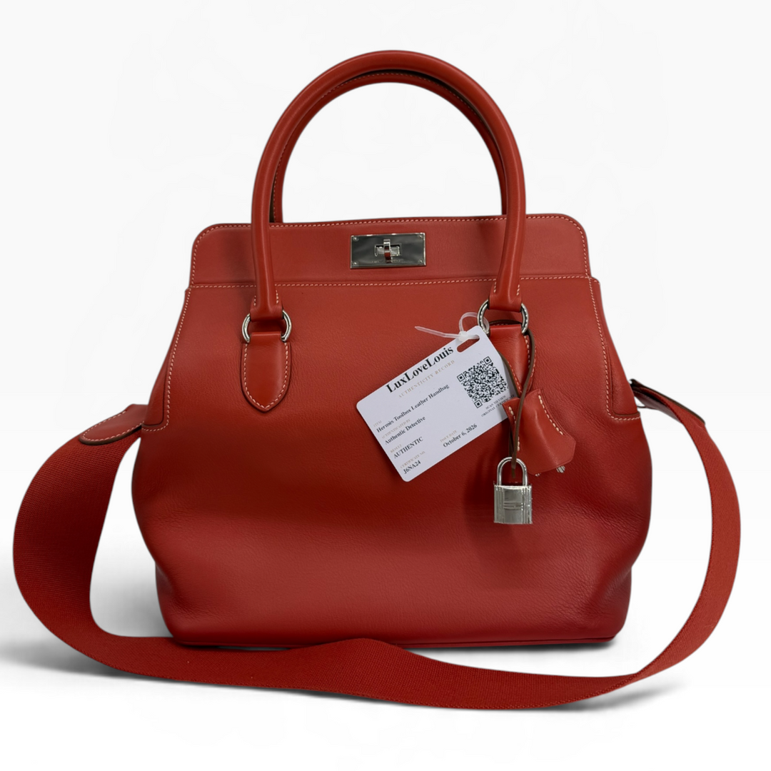 Hermès Toolbox 26 Capucine orange Swift leather handbag front with palladium turn-lock, rolled handles and textile shoulder strap