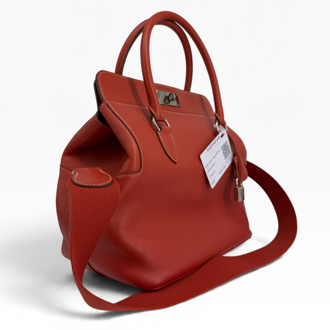 Hermès Toolbox 26 Capucine leather handbag angled front view showing structured handles, shoulder strap and side panel