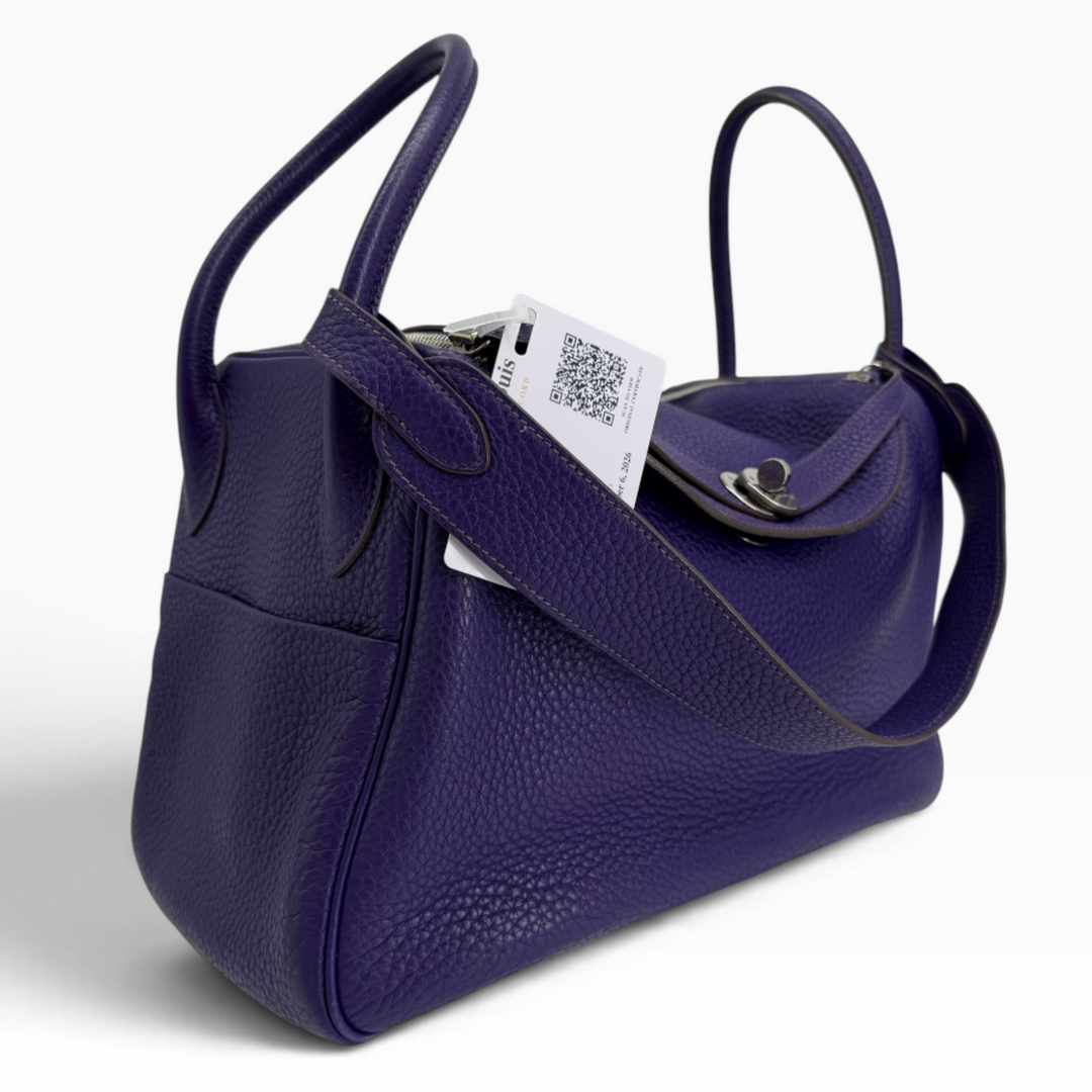 Hermès Lindy 26 Iris purple leather handbag angled front view showing rolled handles, shoulder strap and side pocket