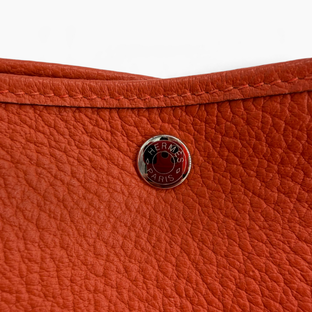 lose-up of Hermès Paris engraved snap on Orange Poppy Negonda leather Garden Party 30