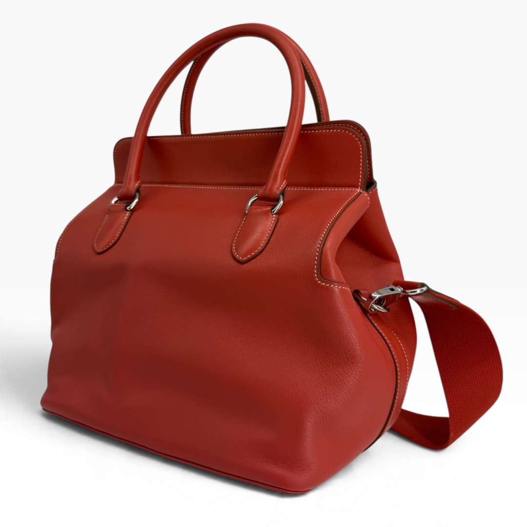 Hermès Toolbox 26 Capucine leather handbag rear three-quarter angle with rolled handles and palladium strap attachment