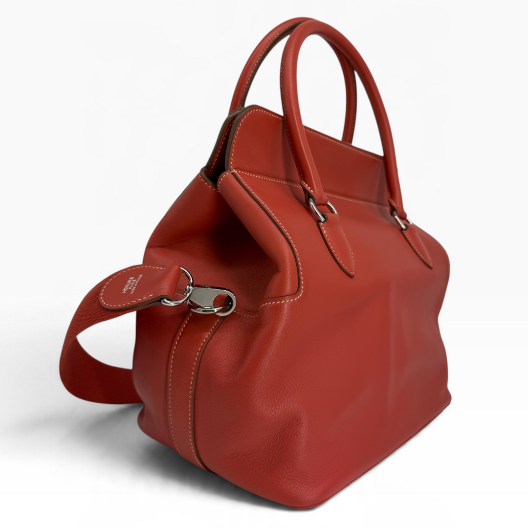 Hermès Toolbox 26 Capucine orange Swift leather opposite angled view showing smooth leather exterior and expandable side