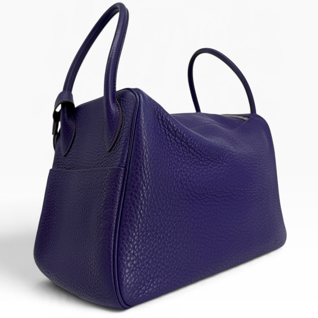 Hermès Lindy 26 Iris purple leather handbag opposite rear angle with rolled handles and structured side panel