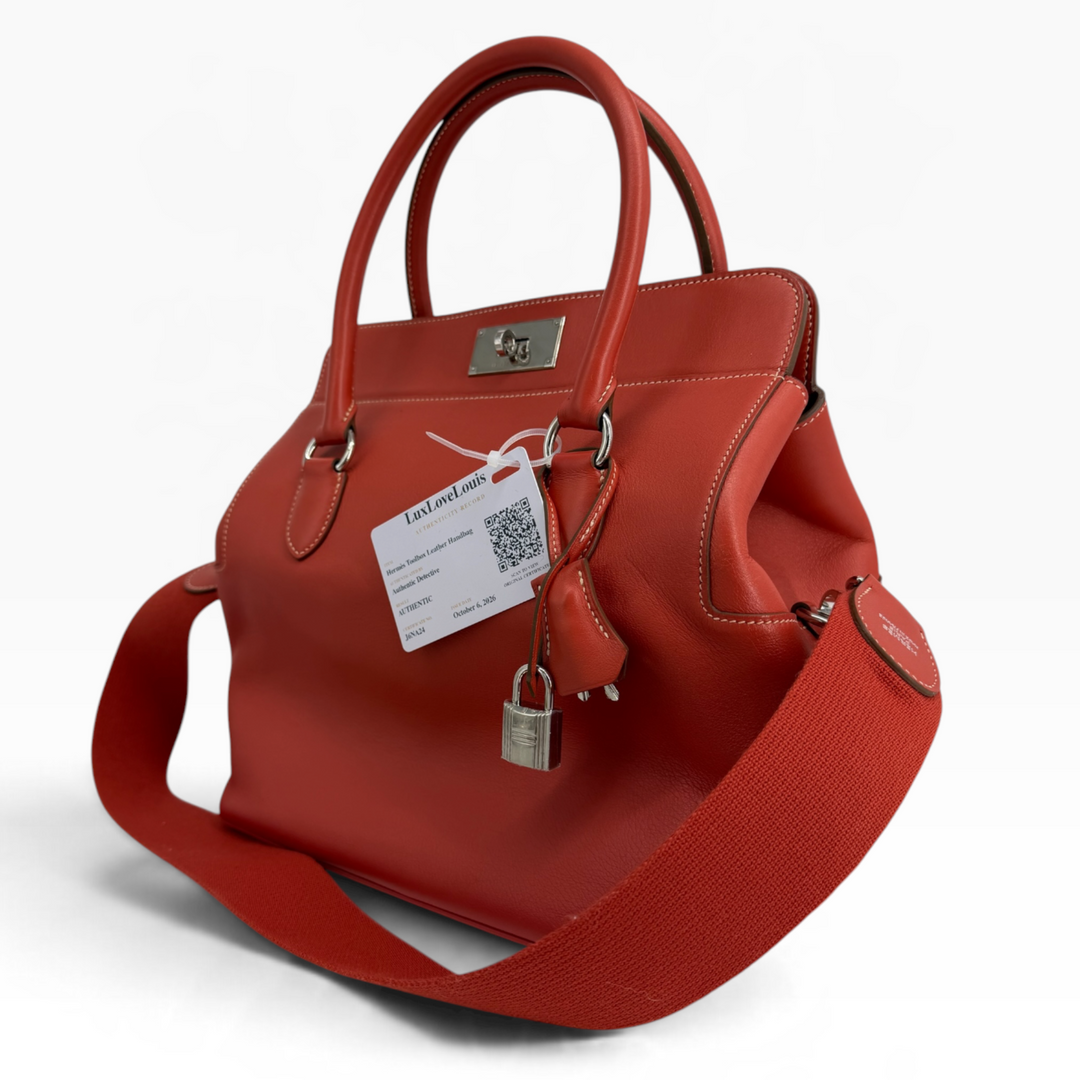 Hermès Toolbox 26 Capucine Swift leather handbag three-quarter front view with turn-lock, clochette, padlock and strap