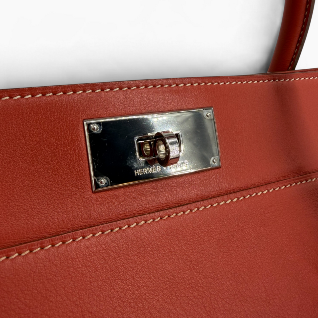 Close-up of Hermès Paris engraved palladium-tone turn-lock hardware on Capucine Toolbox 26