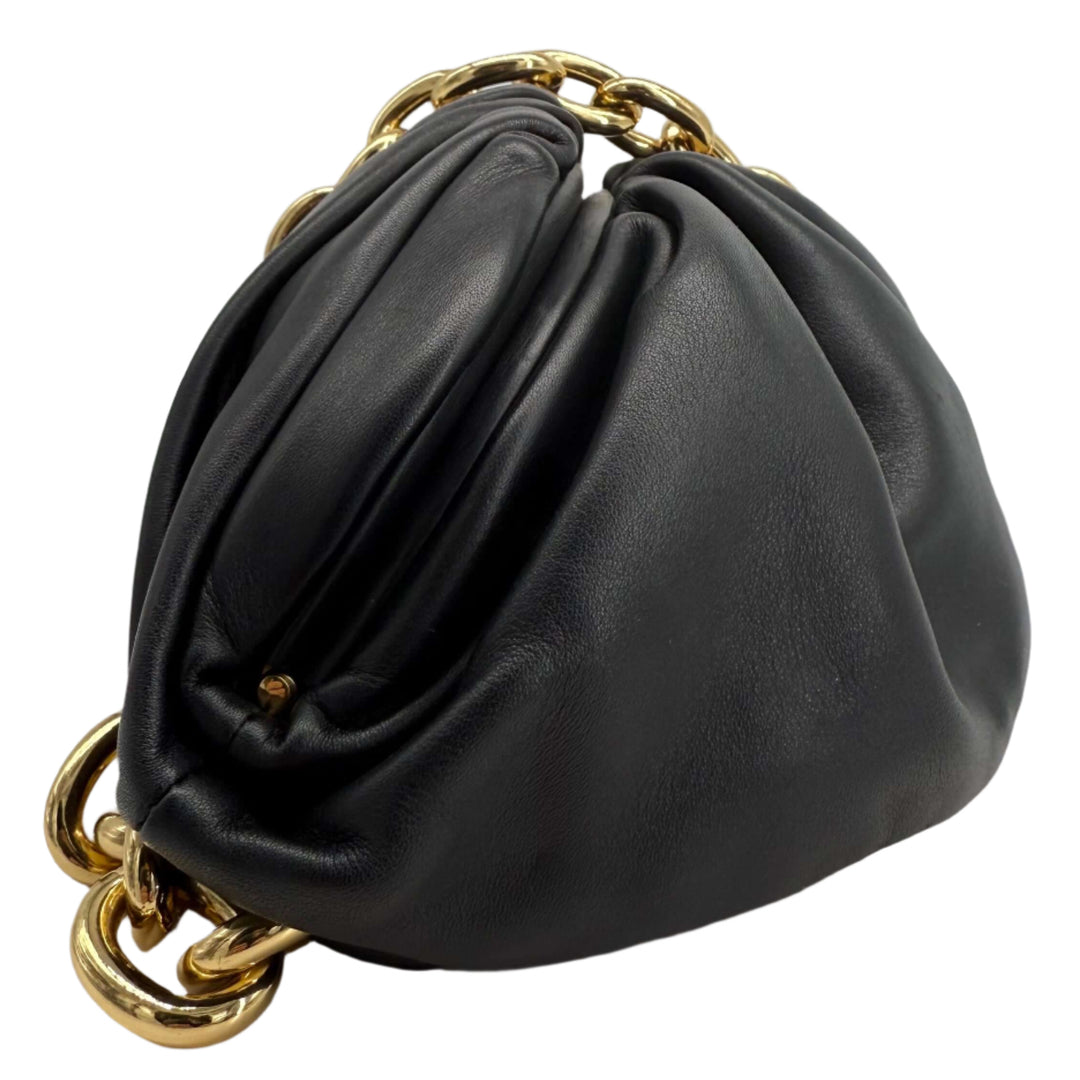 Bottega Veneta The Pouch Chain bag in black calfskin leather with gold chain strap on display.