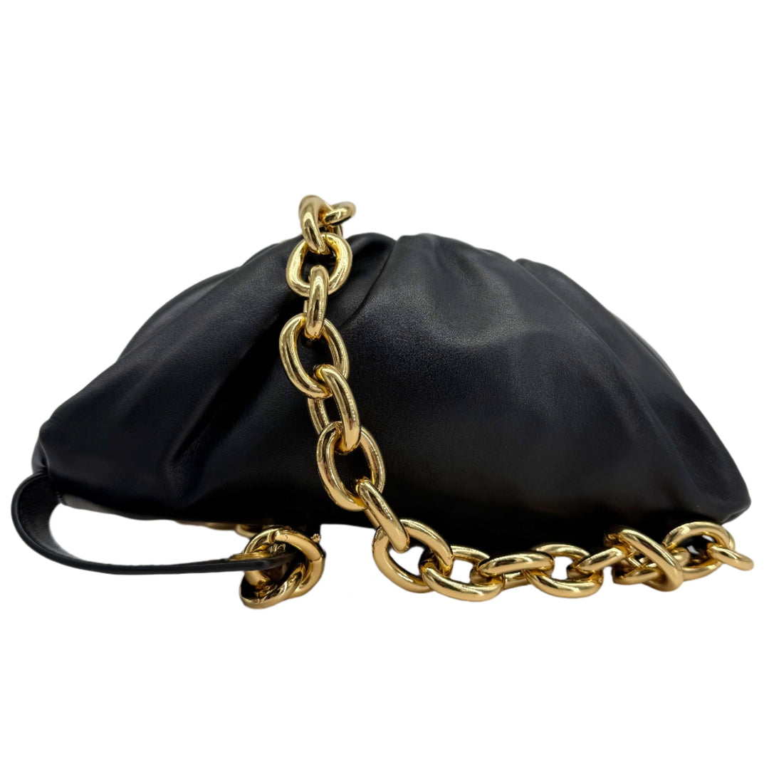 Bottega Veneta The Pouch Chain in black calfskin leather with gold chain strap on a display.