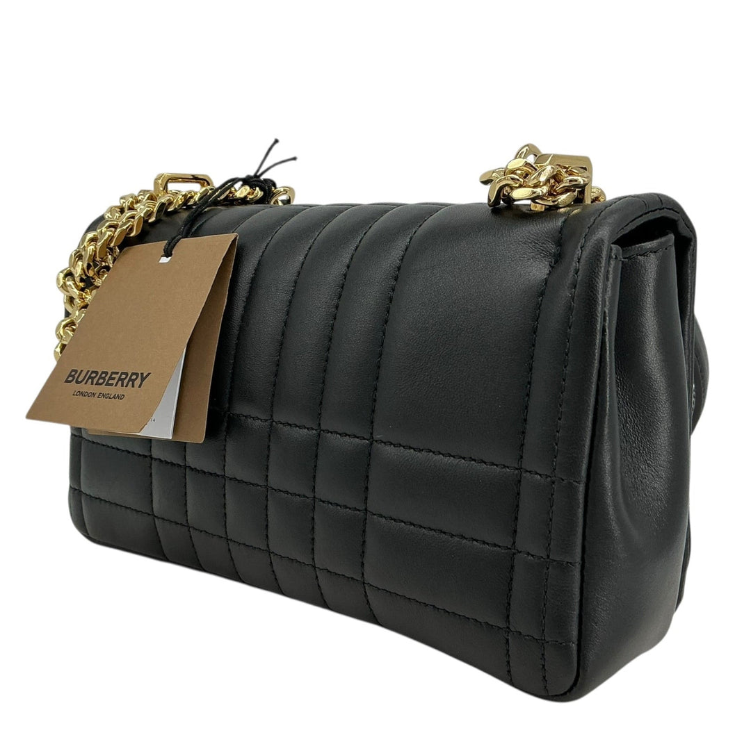 A black quilted leather shoulder bag with gold-tone chain strap details and a hanging Burberry tag, shown on a plain white background.