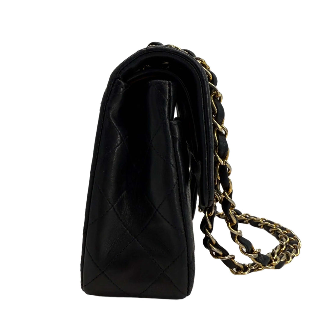 CHANEL lambskin quilted small double flap bag in black with gold hardware, showcasing side view and chain link strap.