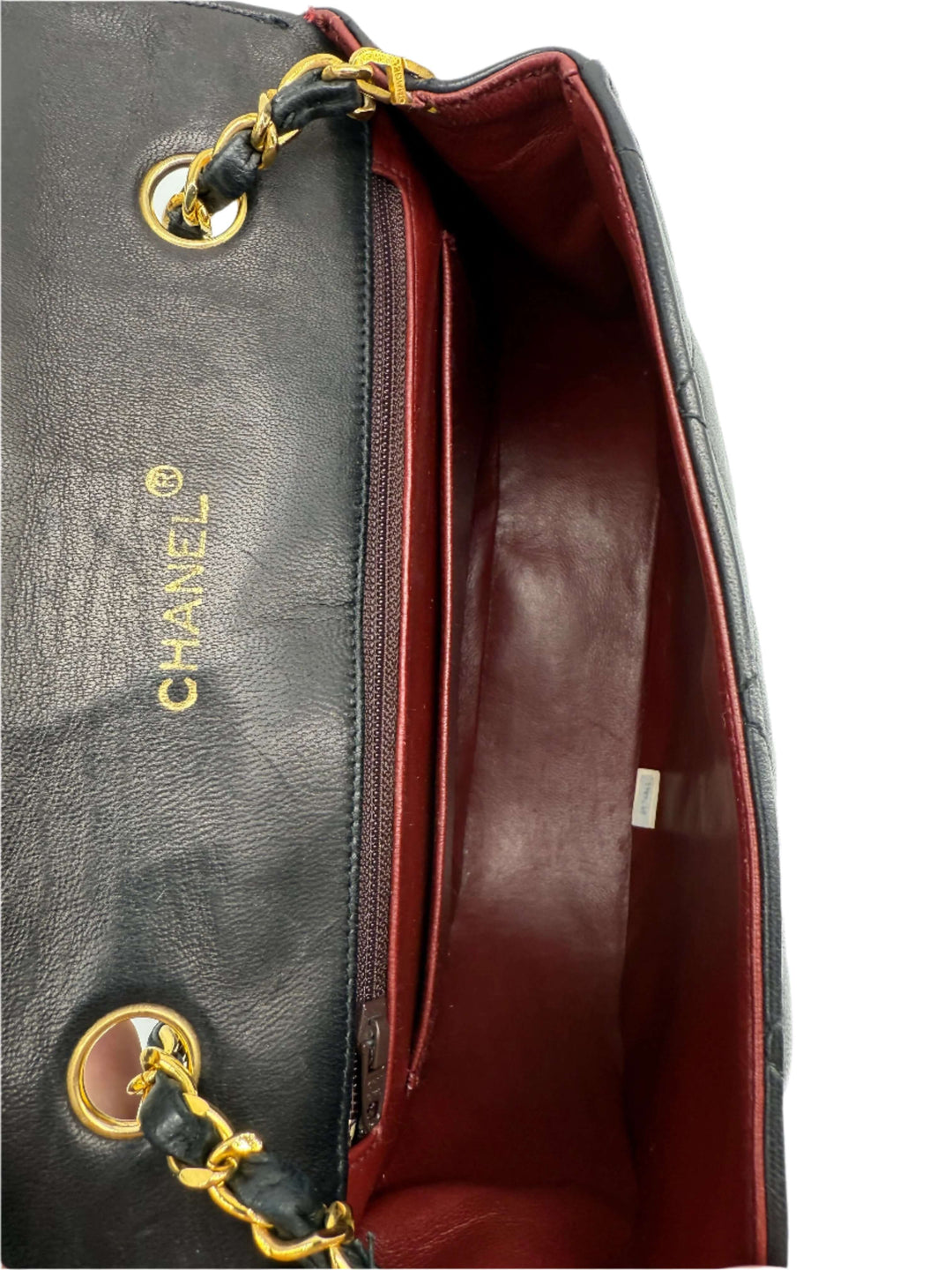 Interior view of Chanel Lambskin Quilted Small Single Flap Bag in black with red lining and gold hardware.