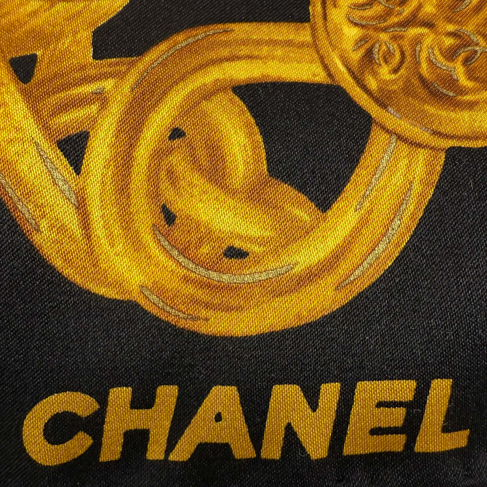 Close-up of CHANEL's vintage silk scarf showcasing a gold jewelry chain print on a black background.