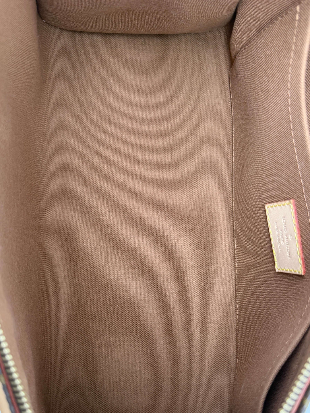 Inside view of the Louis Vuitton Monogram Popincourt Top Handle Handbag showing its clean interior and tag.