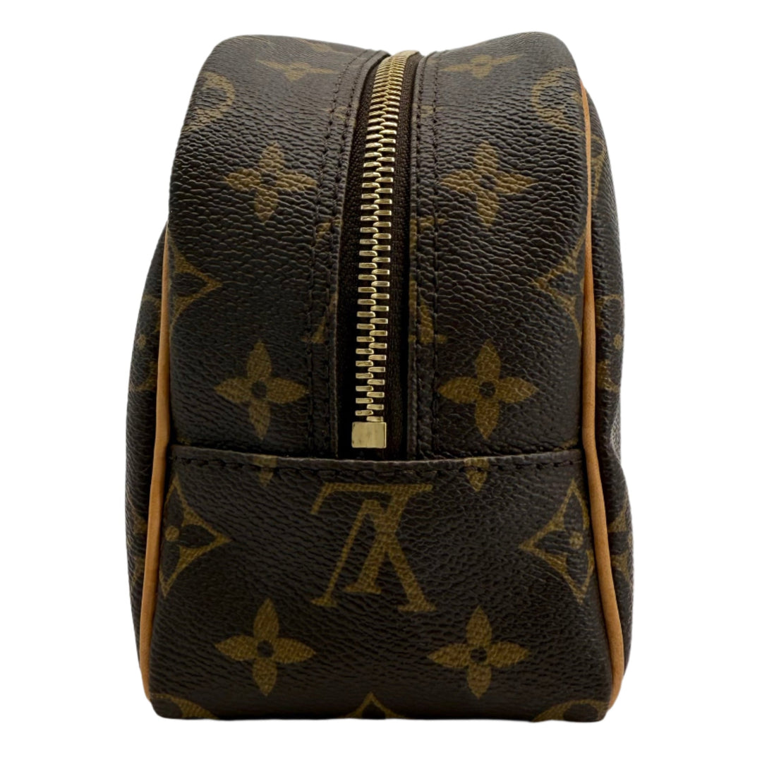 Louis Vuitton Monogram Toiletry Bag 25 side view with gold-tone zipper, crafted from coated canvas and vachetta leather trim.