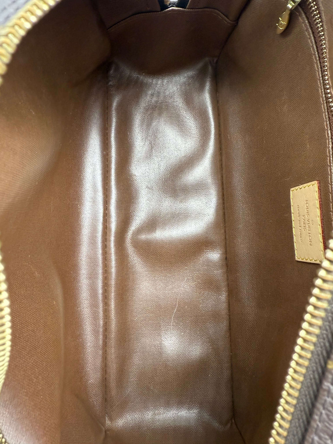 Interior view of Louis Vuitton Monogram Toiletry Bag 25, showcasing the smooth brown lining and spacious storage.
