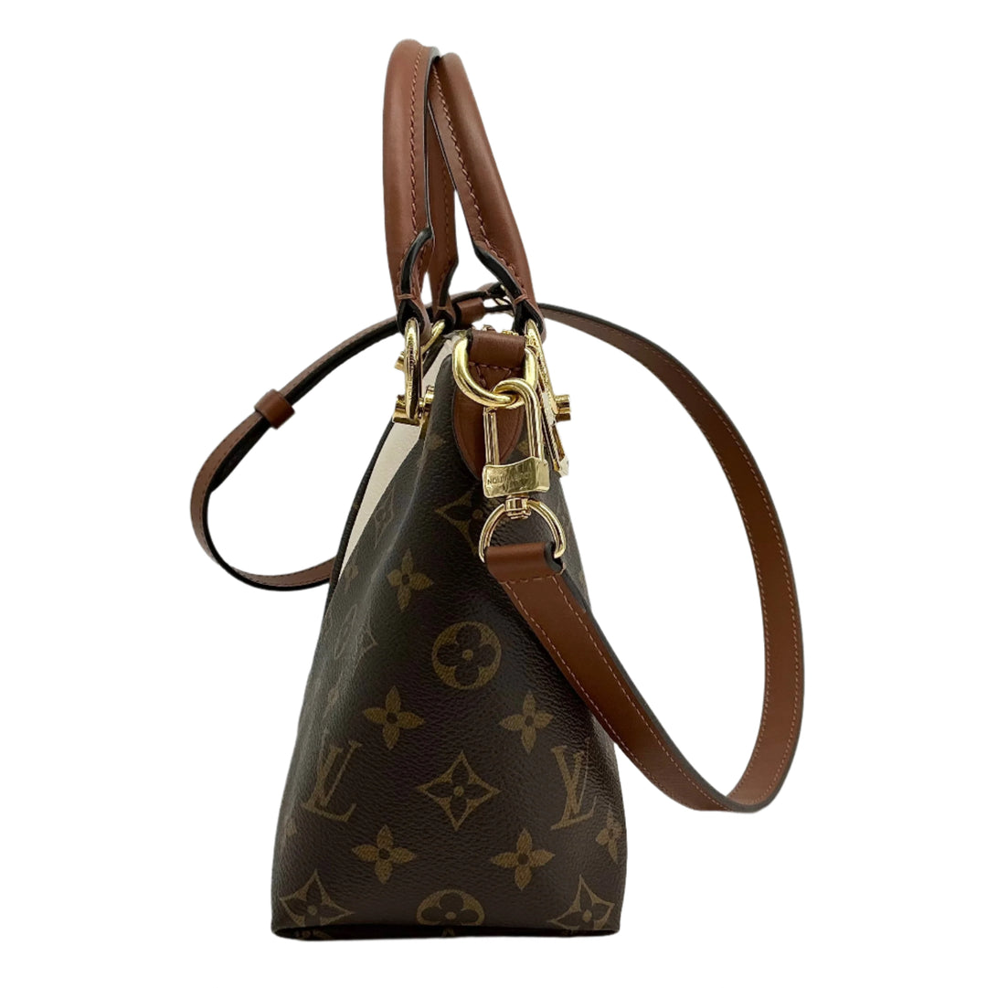 Side view of Louis Vuitton Monogram V Tote BB in Creme with brown leather trim, showcasing luxury and elegance.