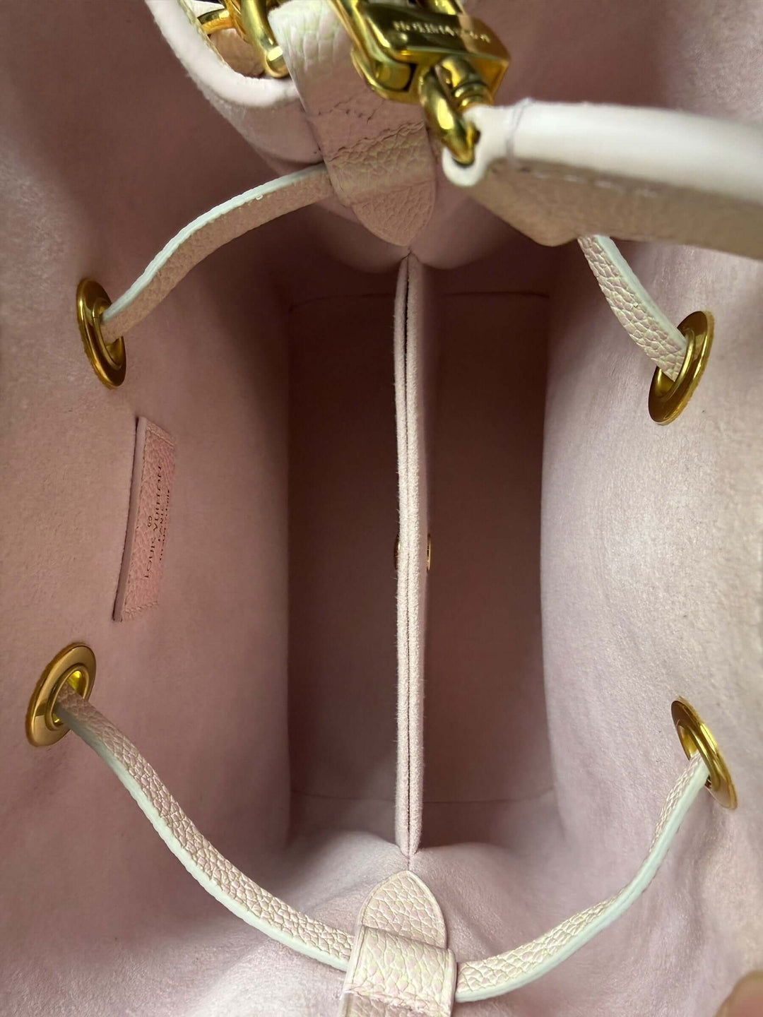 Interior view of Louis Vuitton Empreinte Monogram Summer Stardust Néonoé BB Bucket Bag Pink, featuring gold-tone hardware and divided sections.