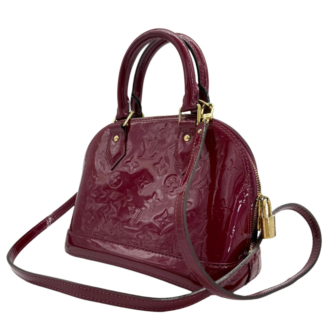 Louis Vuitton Vernis Alma BB in deep magenta patent leather with gold hardware, featuring elegant rolled handles and a stylish design.