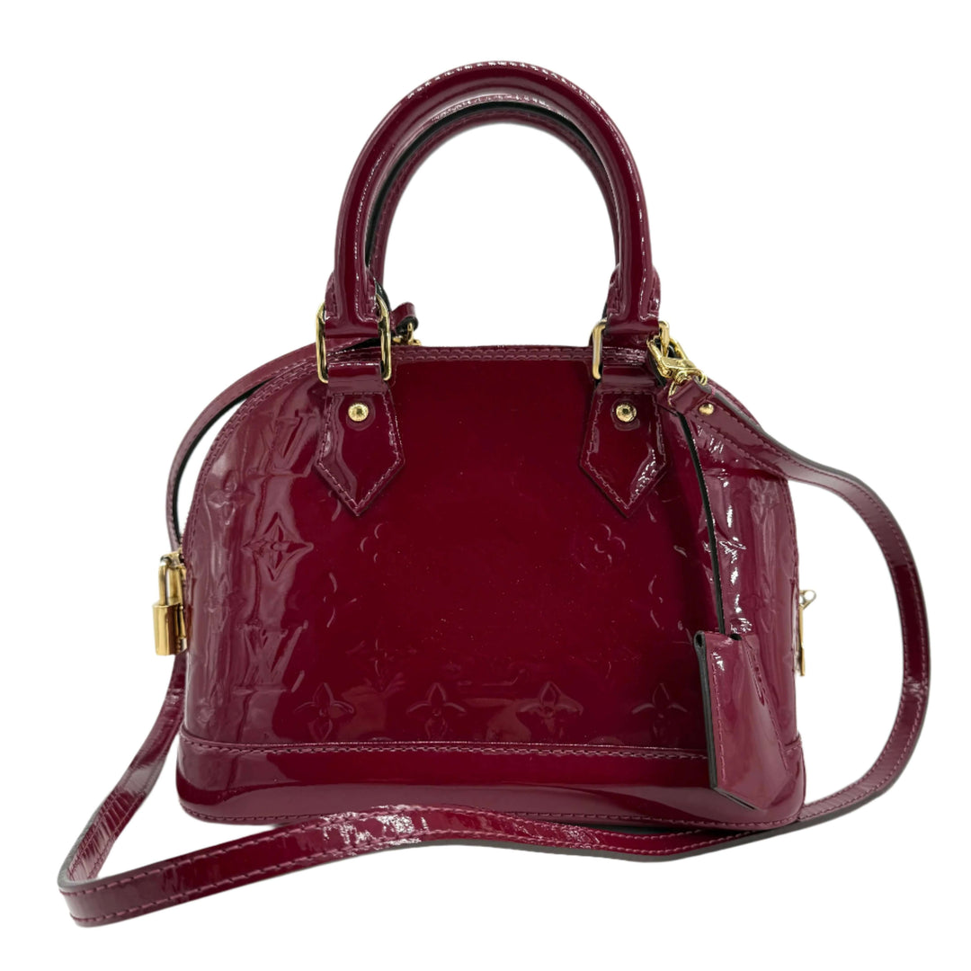 Louis Vuitton Vernis Alma BB bag in deep magenta patent leather with gold hardware, showcasing elegant design.