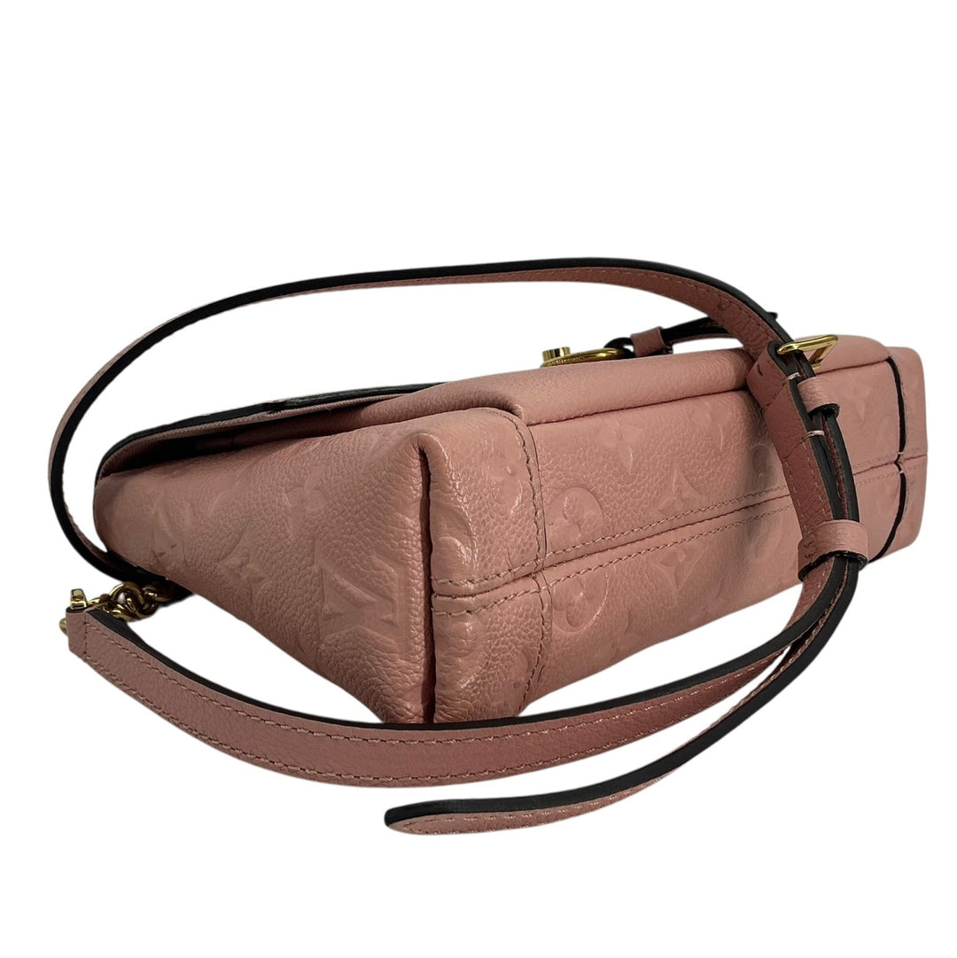 A dusty rose leather shoulder bag with a subtle embossed monogram pattern, gold-tone hardware, and a matching leather strap, shown against a plain white background.