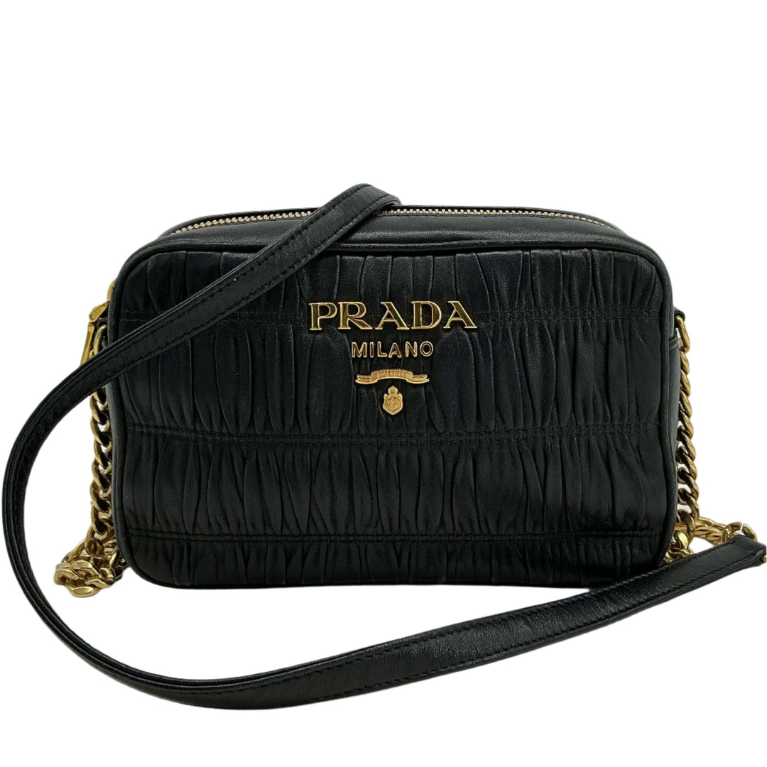 Prada Nappa Gaufre Camera Bag in black pleated lambskin leather with gold-tone chain strap and leather shoulder pad.